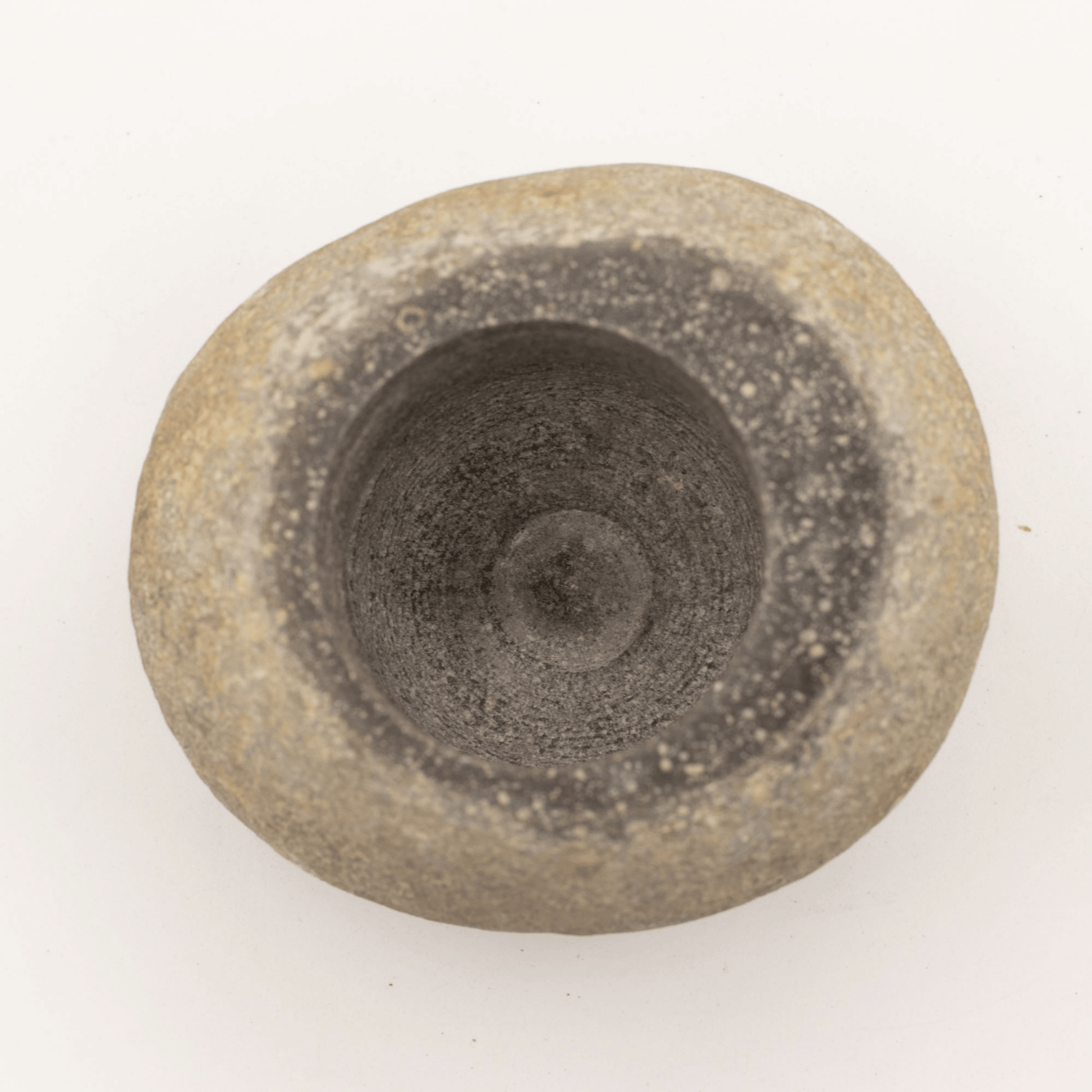Round stone object with concentric circular patterns on a white background