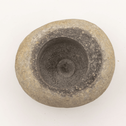 Round stone object with concentric circular patterns on a white background