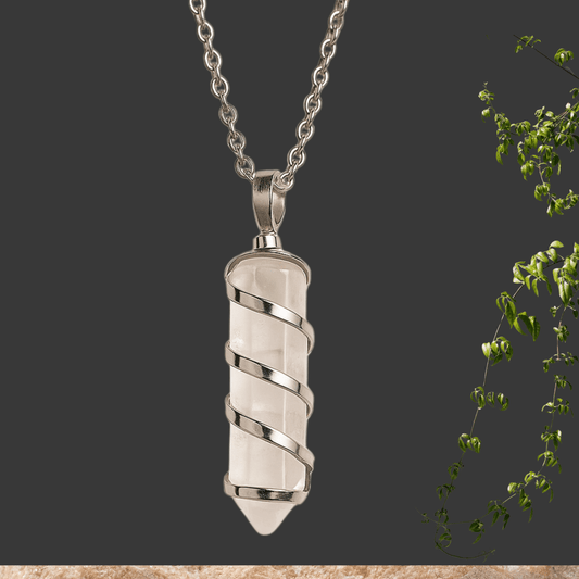 Silver rock  crystal pendant necklace on a dark background with green leaves.