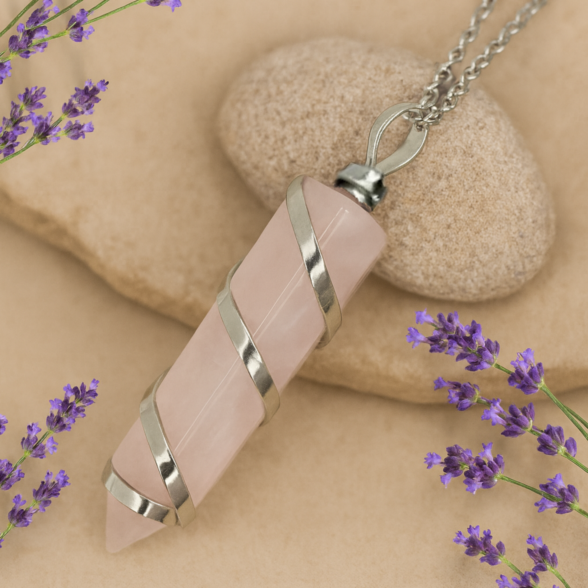 Necklace with pink rose quartz stone pendant on a beige background with lavender flowers