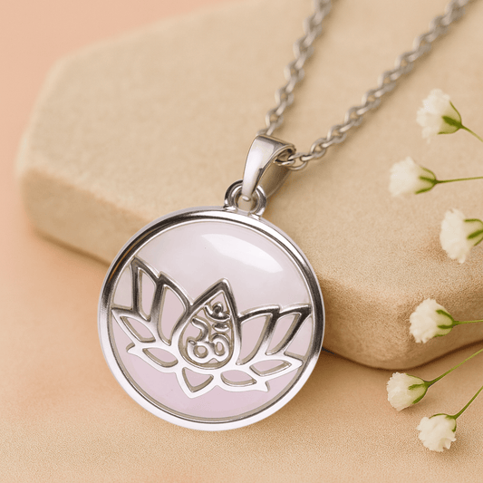 Silver necklace with a round pendant featuring a lotus flower with OM symbol design on a beige background with white flowers.