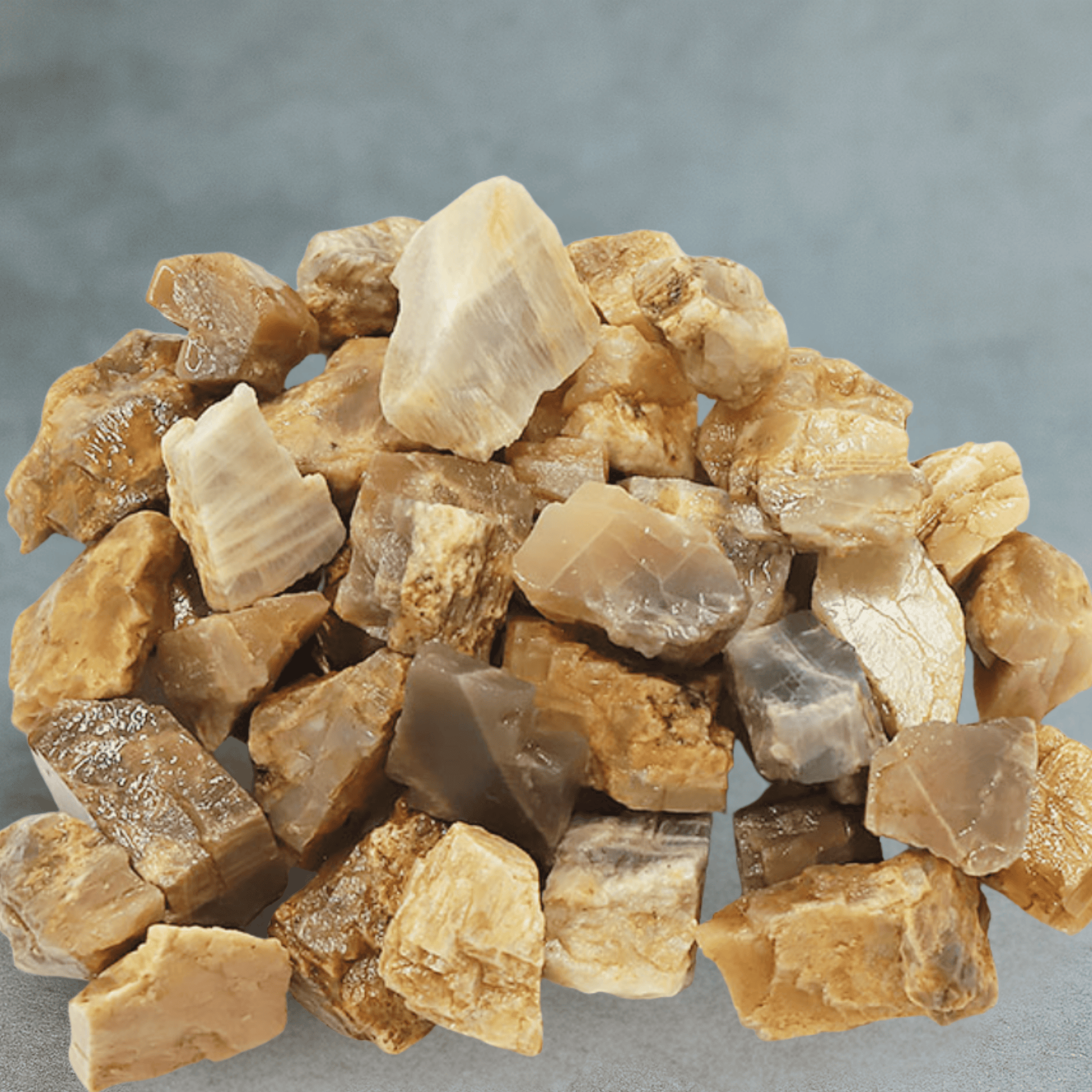 Pile of rough moonstone stone or crystal pieces on a gray background