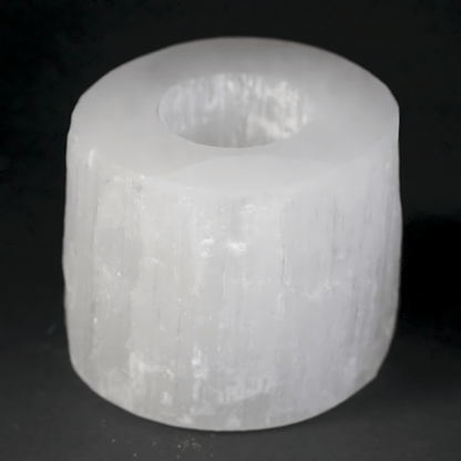 White Selenite cylindrical object with a central hole on a black background