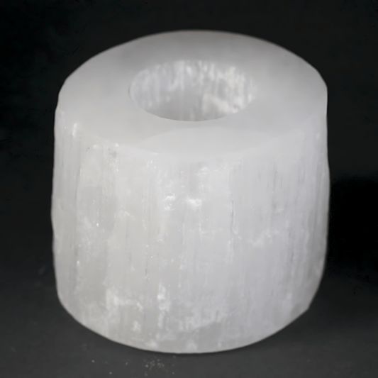 White Selenite cylindrical object with a central hole on a black background