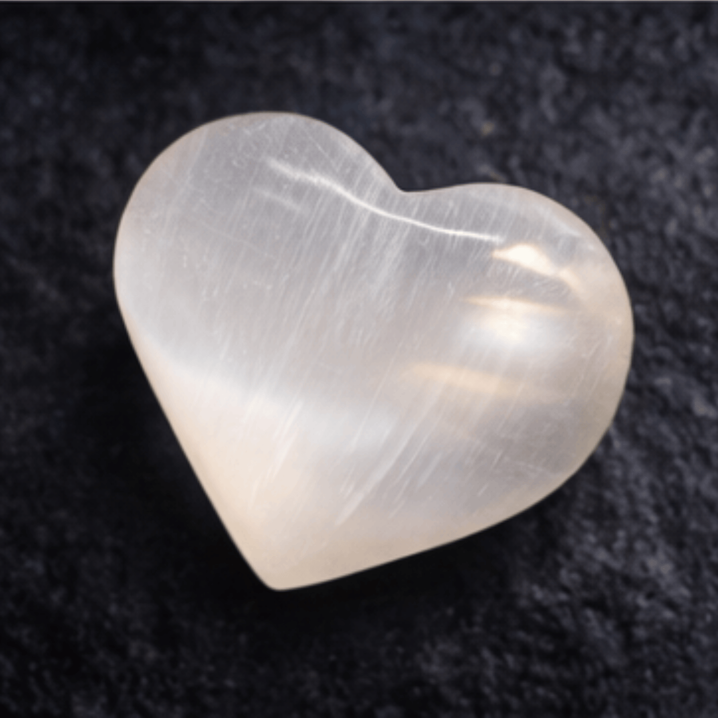 Heart-shaped Selenite Crystal on a dark textured background