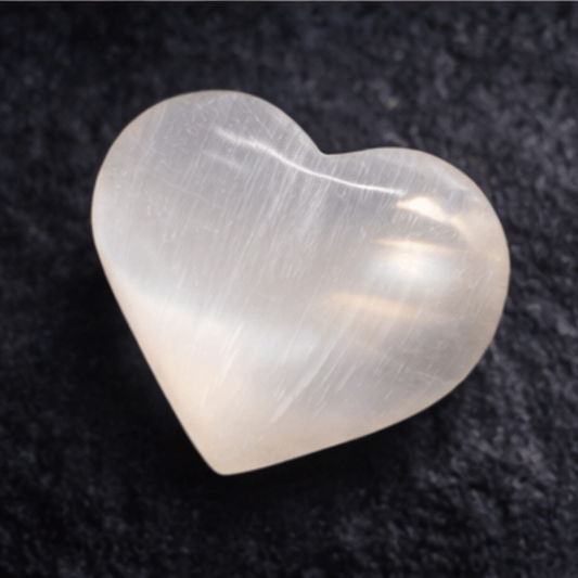 Heart-shaped Selenite Crystal on a dark textured background