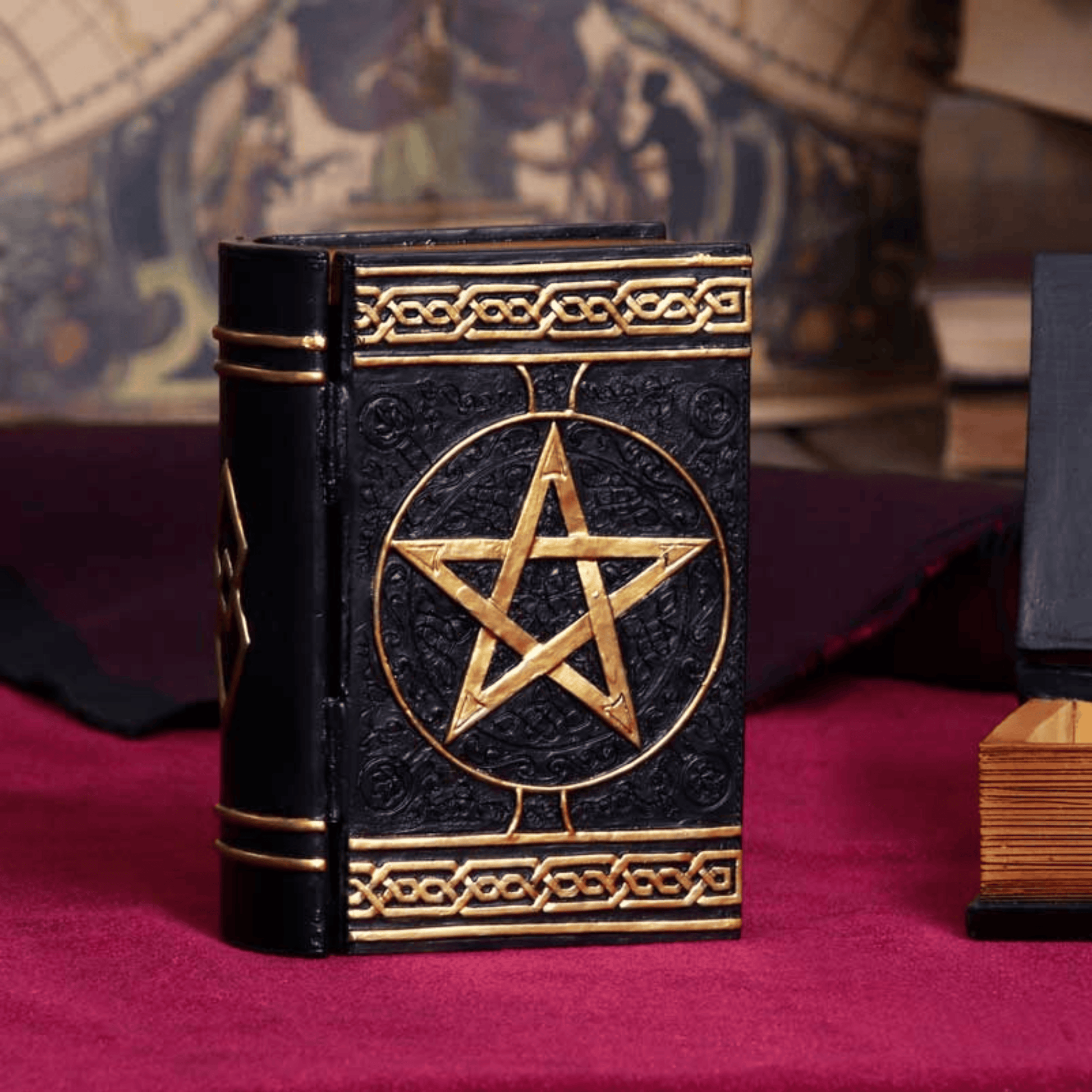 Black book box with gold pentagram design on a red surface