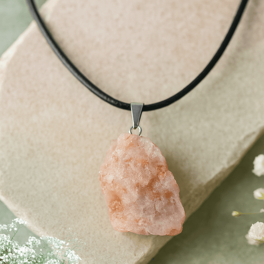 Necklace with a orange sunstone pendant on a light stone surface