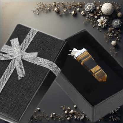 Crystal in an open black gift box with decorative elements on a dark surface
