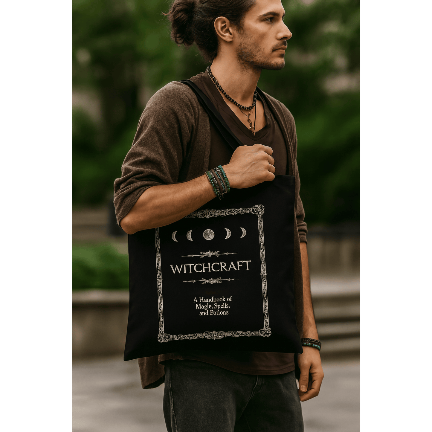 Man holding a black tote bag with 'Witchcraft' text and moon phases design.