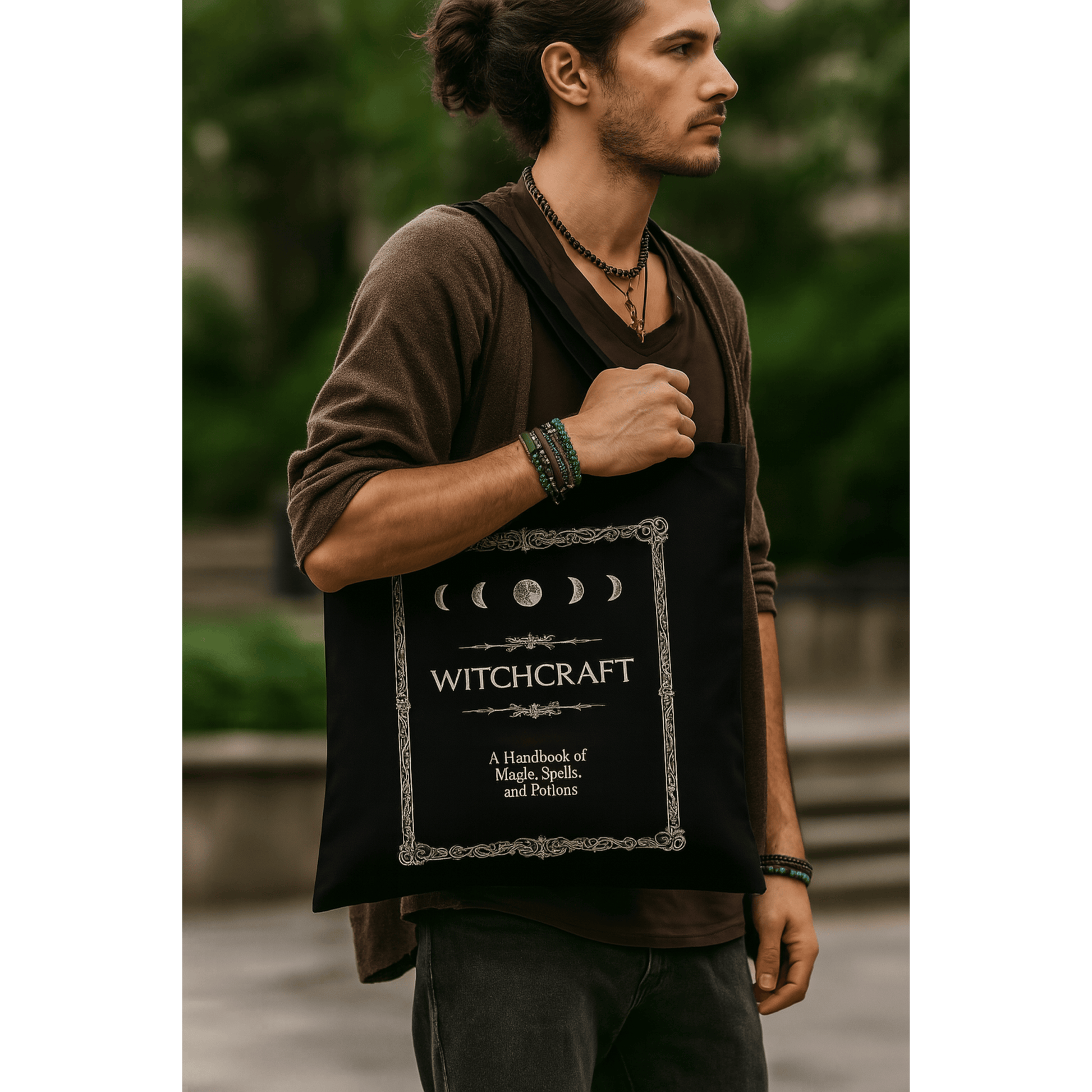 Man holding a black tote bag with 'Witchcraft' text and moon phases design.