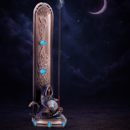 Decorative incense burner with mermaid figure and blue stones against a dark background