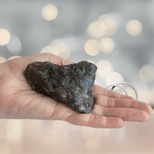 Large Labradorite crystal on the palm of a adult hand and sequence in the background