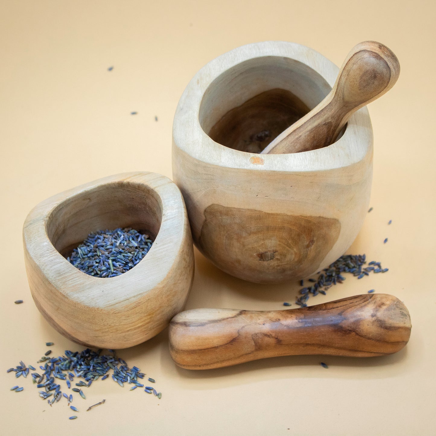 Wooden mortar and pestle with lavender on a beige background