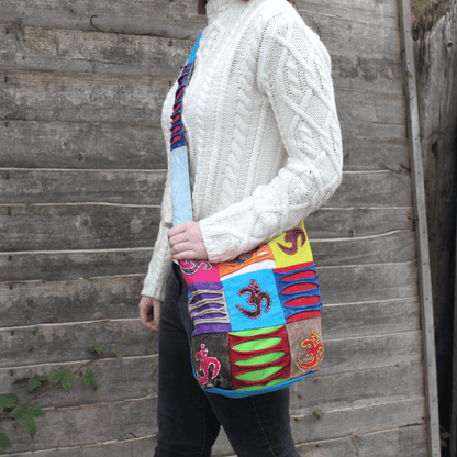 Person wearing a colorful patchwork bag against a wooden wall.